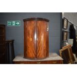 A late 19th/early 20th century mahogany inlaid corner cabinet of barrel form