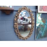 Oval bevelled mirror in decorative gilt frame