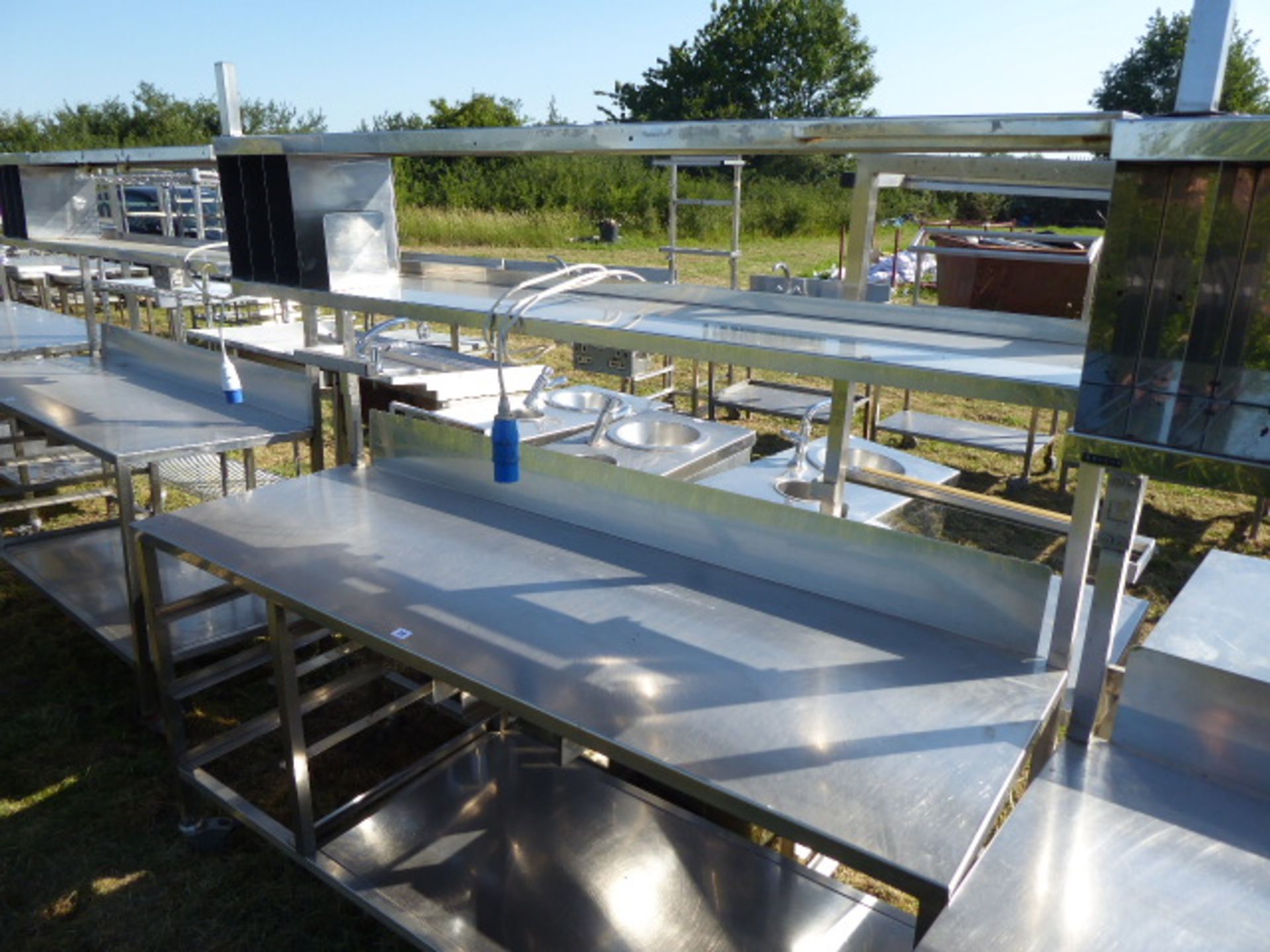 Stainless steel mobile food preparation station with 2 shelves over, shelf under space for trays,