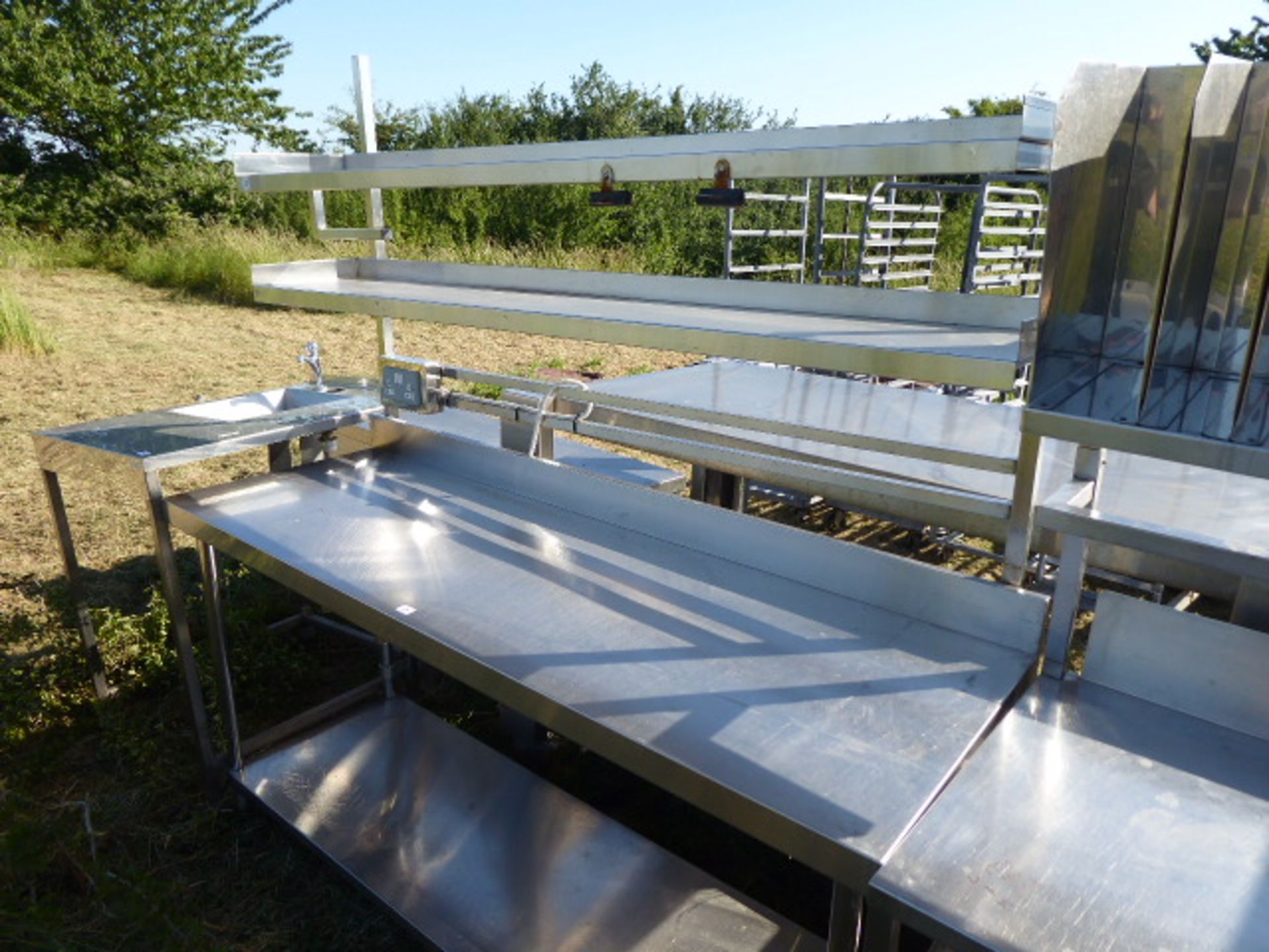 Stainless steel mobile food preparation station with 2 shelves over, shelf under space for trays,