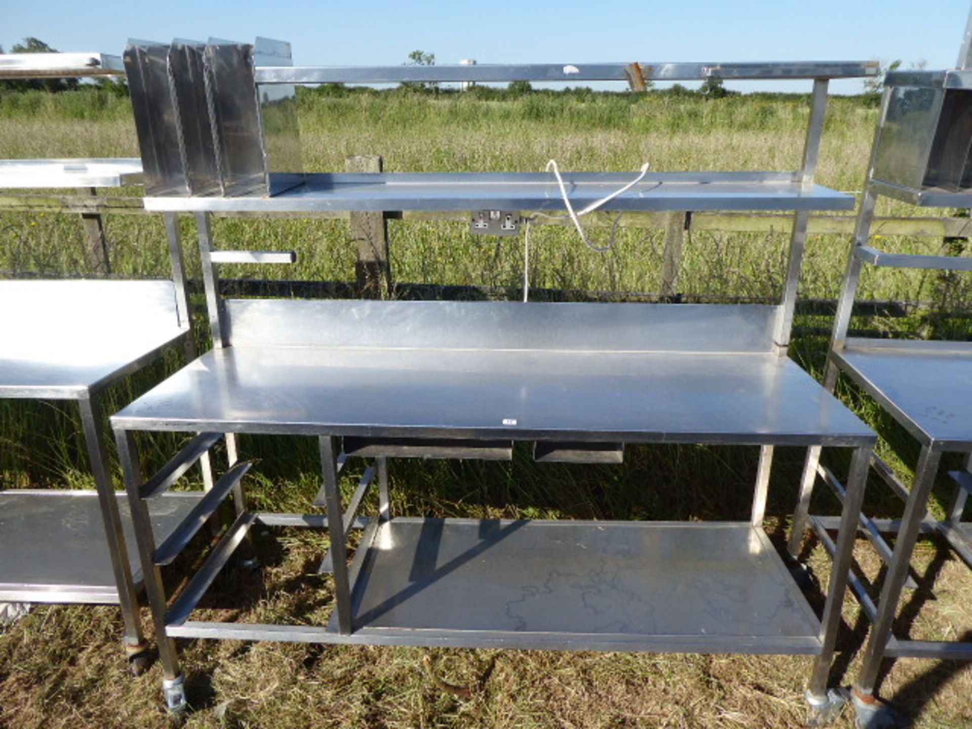 Stainless steel mobile food preparation station with 2 shelves over, shelf under space for trays,