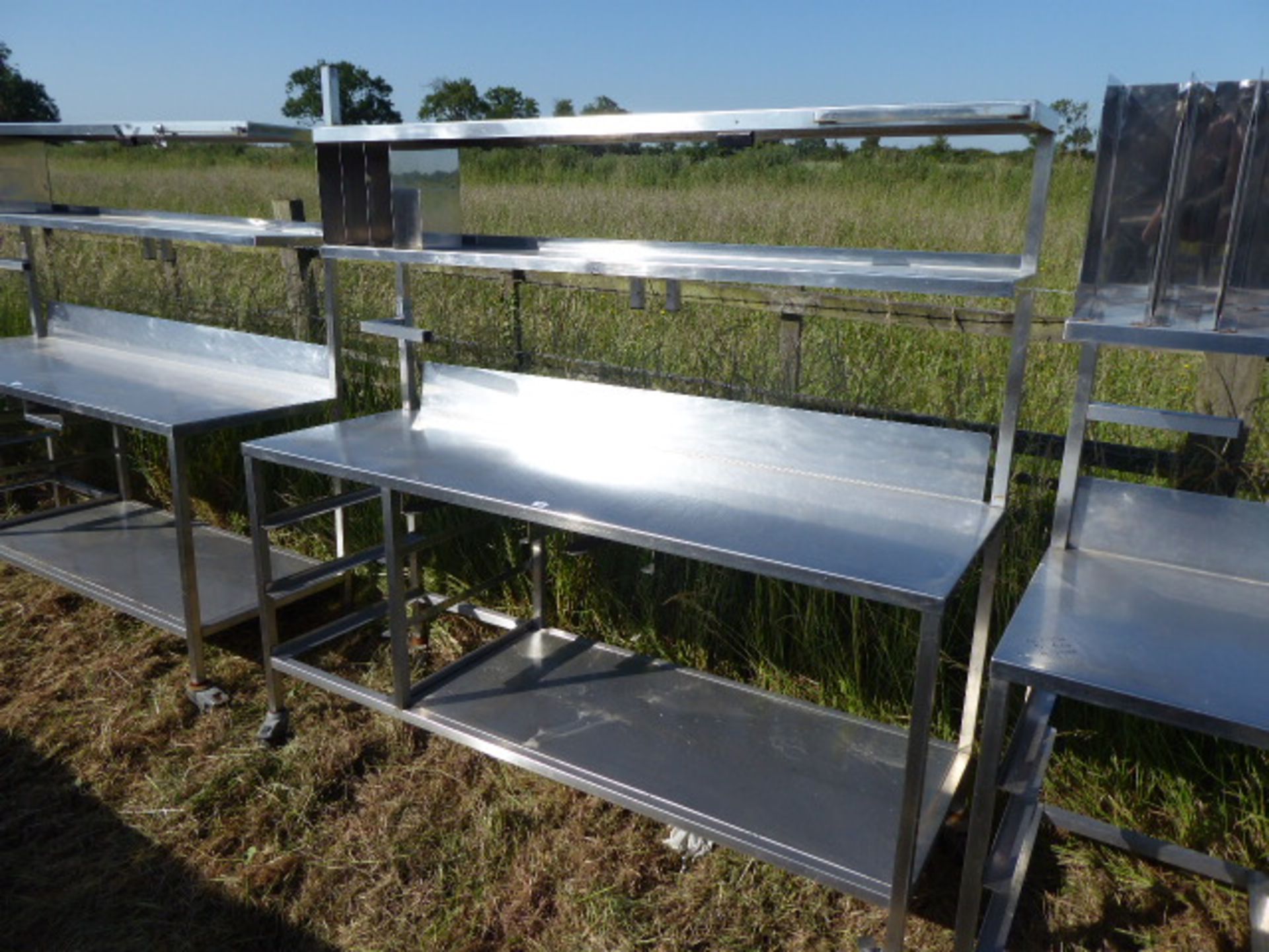 Stainless steel mobile food preparation station with 2 shelves over, shelf under space for trays,