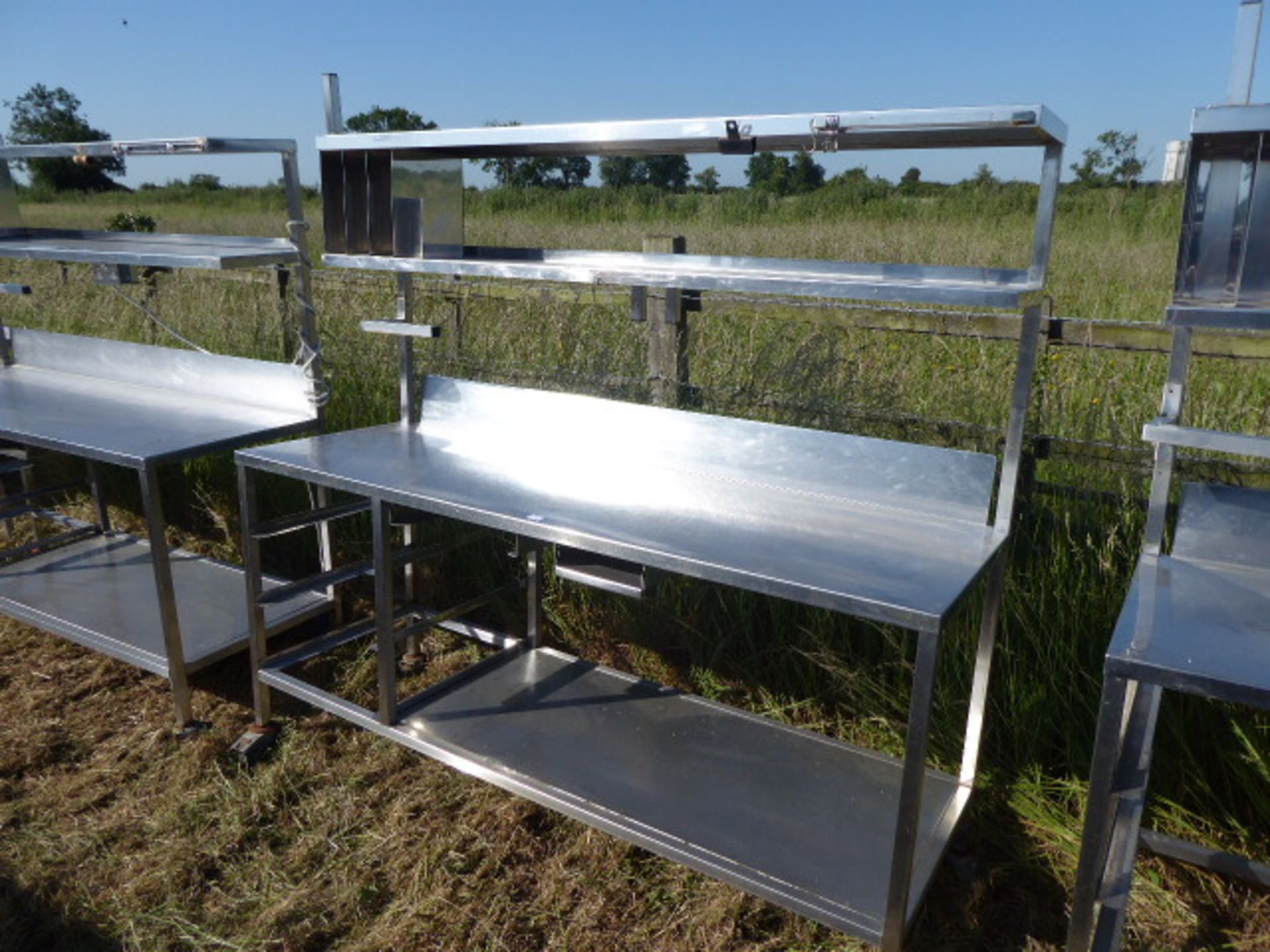 Stainless steel mobile food preparation station with 2 shelves over, shelf under space for trays,