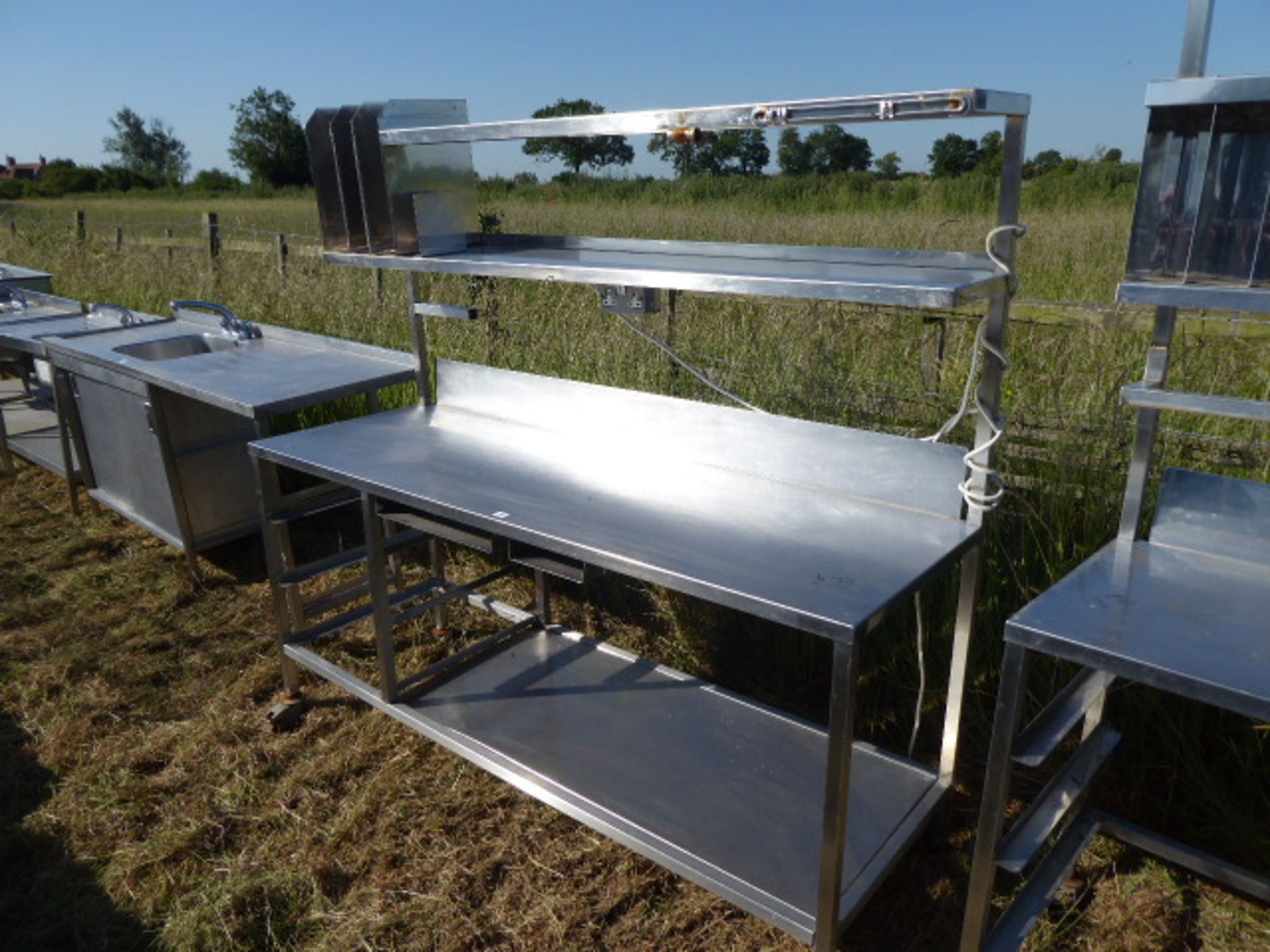 Stainless steel mobile food preparation station with 2 shelves over, shelf under space for trays,