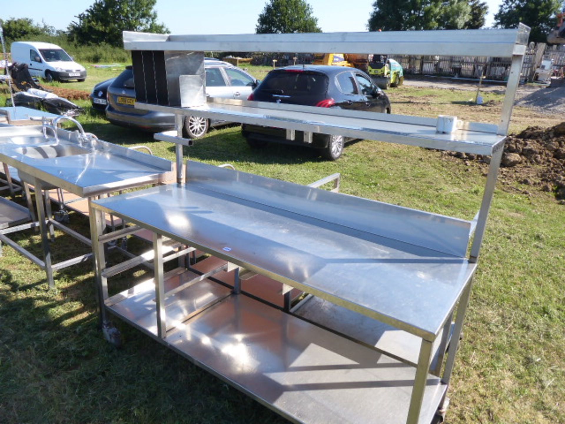 Stainless steel mobile food preparation station with 2 shelves over, shelf under space for trays,