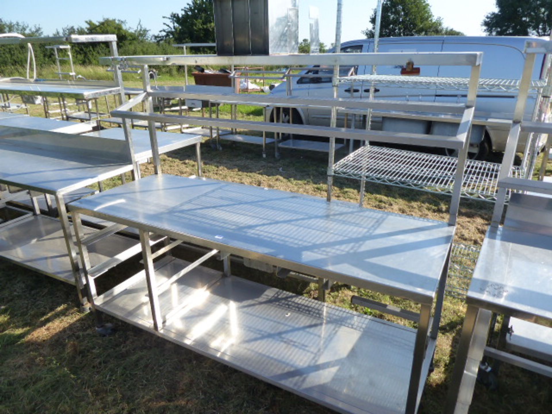 Stainless steel mobile food preparation station with 1 shelf over, shelf under space for trays and a