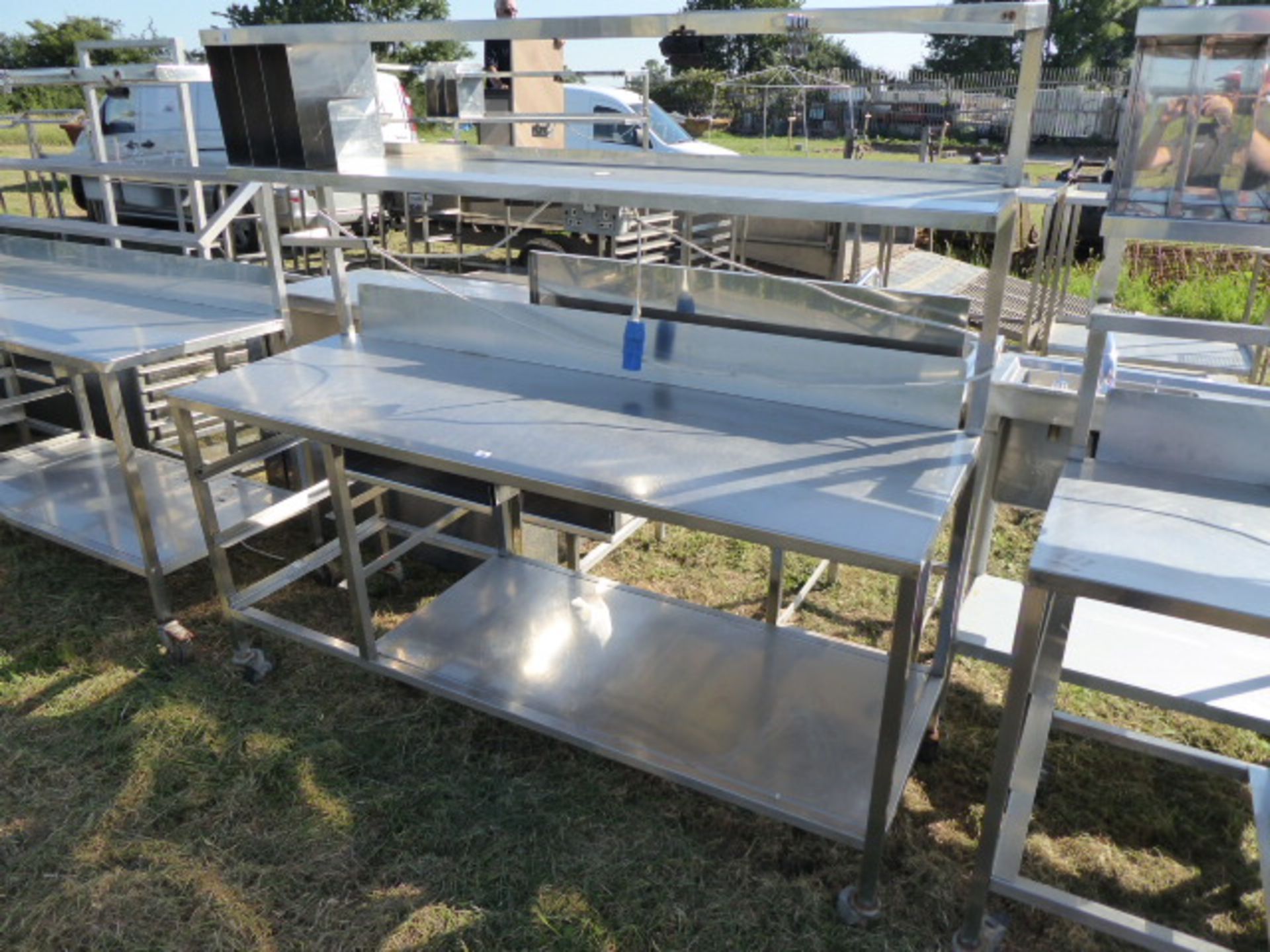 Stainless steel mobile food preparation station with 2 shelves over, shelf under space for trays,