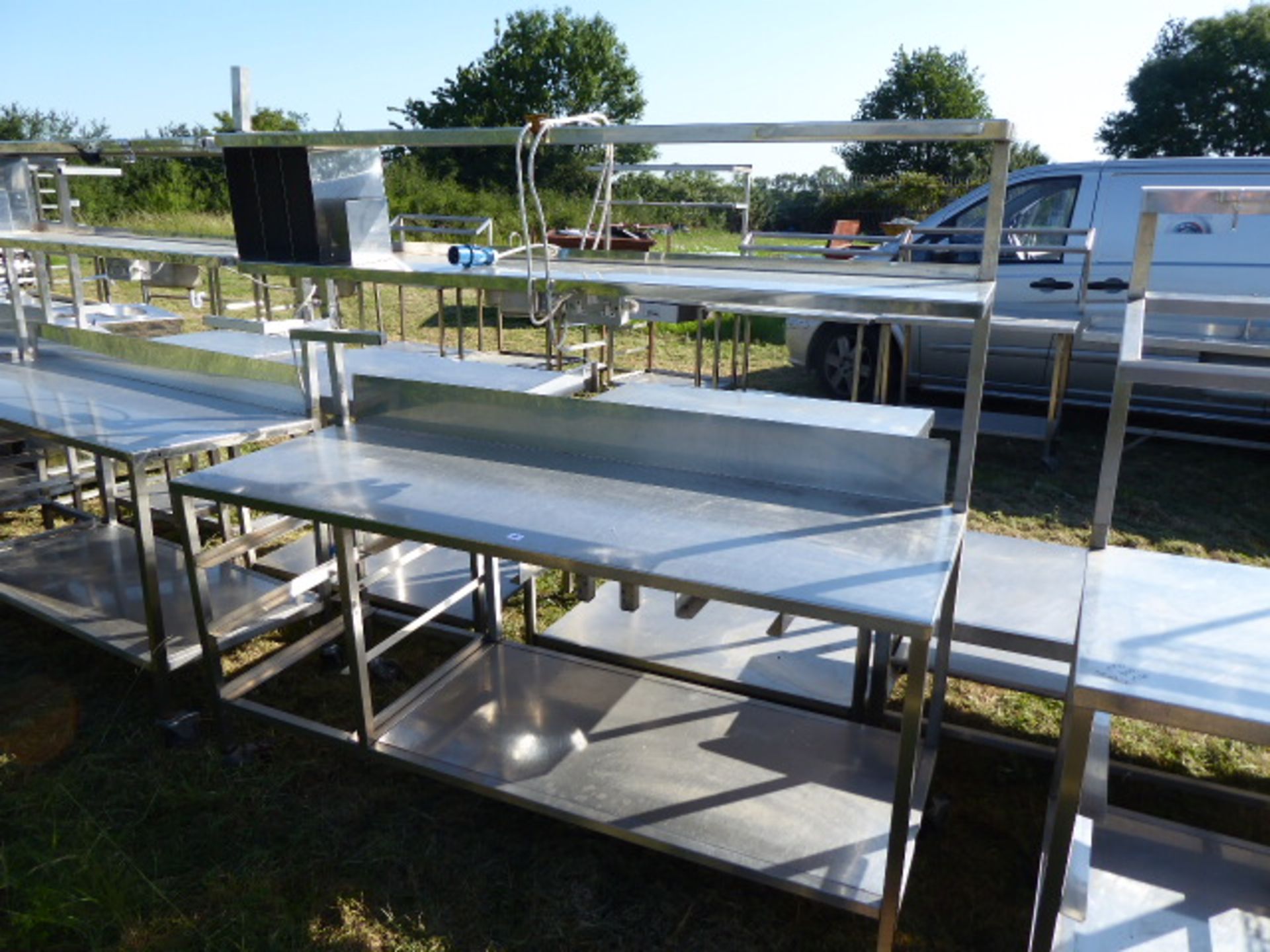 Stainless steel mobile food preparation station with 2 shelves over, shelf under space for trays,