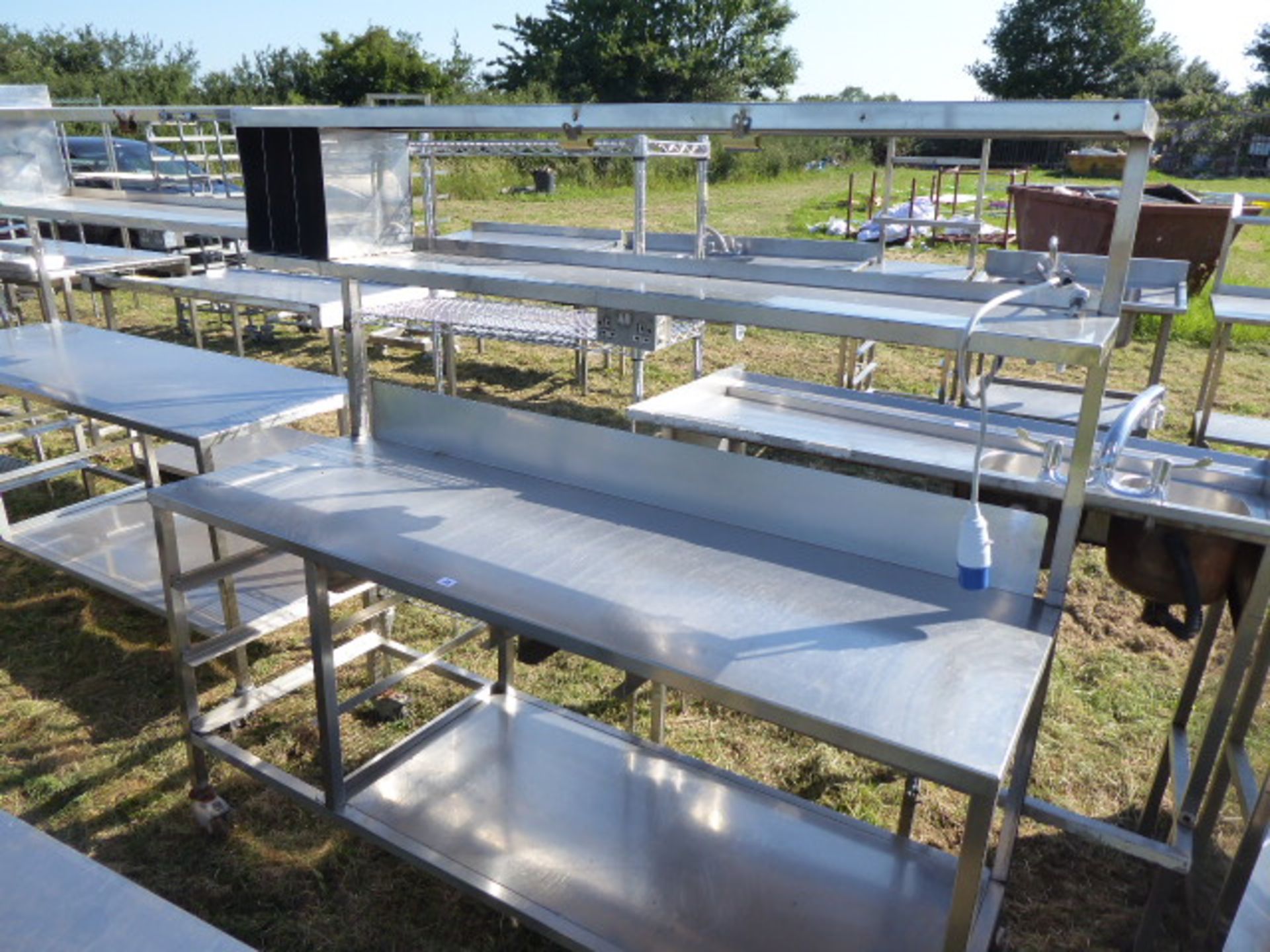 Stainless steel mobile food preparation station with 2 shelves over, shelf under space for trays,