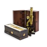 A late 19th century brass microscope in a fitted case together with a box of slides