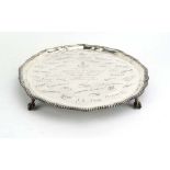 A silver salver of circular form with piecrust border on four claw and ball feet,