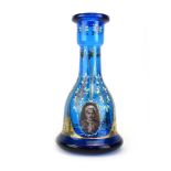 An early 20th century kingfisher blue glass decanter of mallet form decorated with a portrait of an