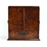 A Victorian walnut smokers cabinet, the two doors enclosing two drawers and a compartment,