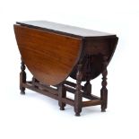 An 18th century oak gateleg table with a single frieze drawer on turned supports joined by