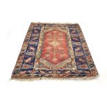 A Turkish woolen rug with a central red ground and blue borders,