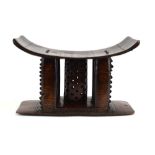 An Ashanti Tribal stool with pierced supports and a shaped seat, h.