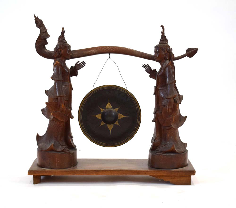 A Tibetan metal gong suspended on a pair of wooden standing figures CONDITION REPORT: