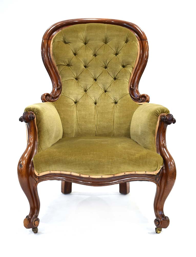 A 19th century mahogany and button upholstered armchair with scrolled arms and matching feet on