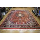 An Iranian hand-made carpet, the red ground with a central medallion,