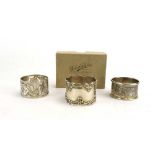 A pierced silver and florally decorated napkin ring, together with two further napkin rings,