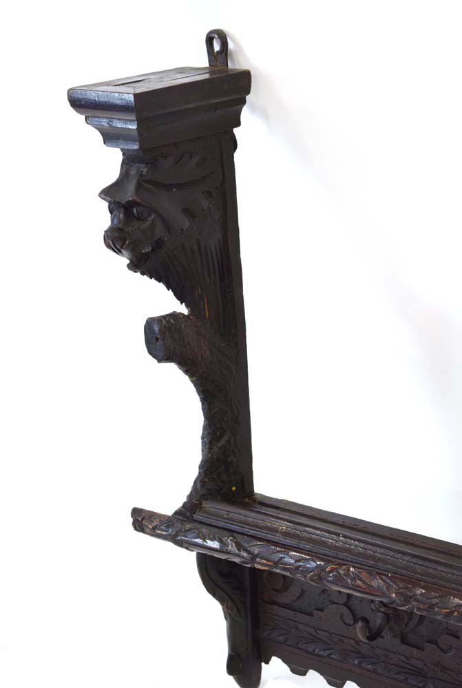 A carved oak hall shelf with figural flanks and four mask head hooks, - Image 2 of 4