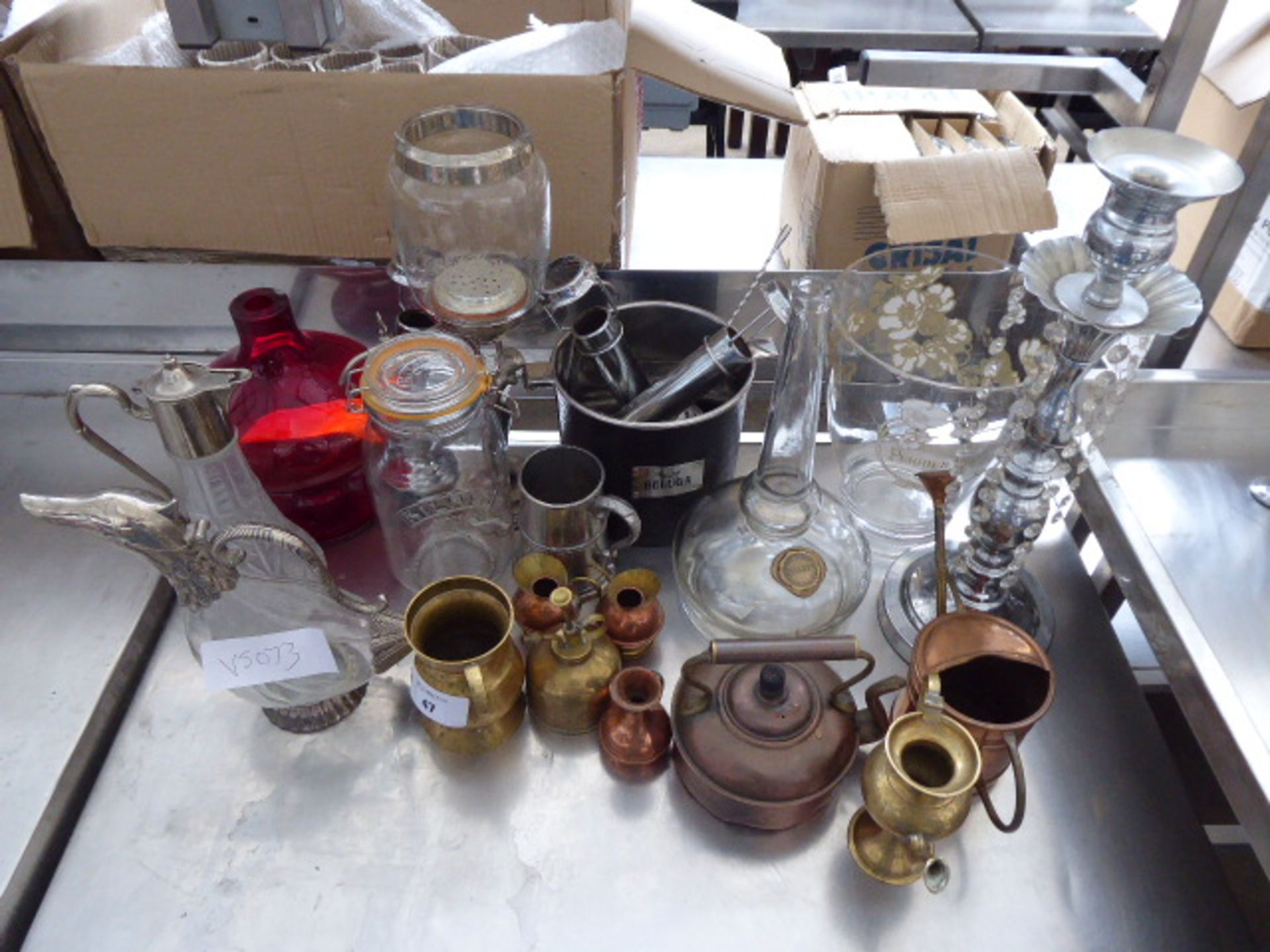 Tabletop display of assorted decorative items including carafes, brass and copper wares, champagne