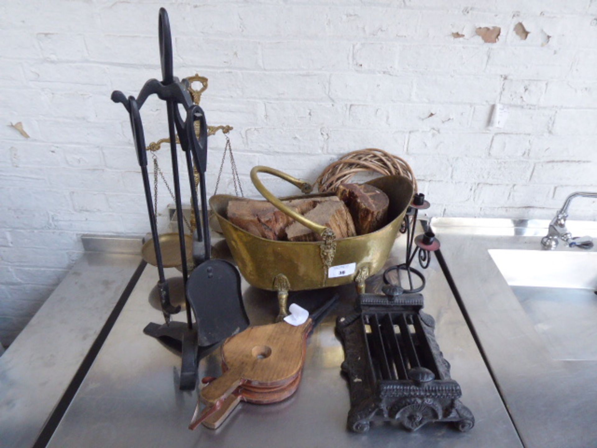 Tabletop of display items including boot scrape, mini bellows, coal scuttle, balance scales etc