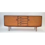 A 1960's teak sideboard, the four drawers with integral handles and flanked by two doors,