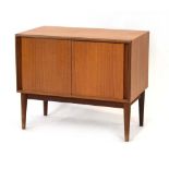 A 1970's teak cabinet with two sliding doors on interlocking runners, on tapering legs, w.