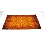 A 1970's woolen rug with a yellow and brown ground and a flowerhead motif,