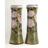 A pair of Royal Doulton slender vases relief decorated with roses in full bloom on a mottled green