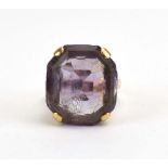 A 9ct yellow gold dress ring set amethyst coloured stone in a raised scrollwork setting,