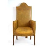 An early 20th century highback leather and studded armchair on tapering legs with pad feet,