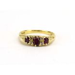 An 18ct yellow gold ring set three graduated rubies interspersed with four small diamonds in a