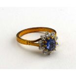 An 18ct yellow gold cluster ring set pale oval sapphire within a border of ten small brilliant cut