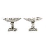 A pair of late Victorian silver tazza of scalloped design, each raised on a Rococo design foot,