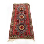 A mid-20th century runner decorated with a red ground and repeated motifs,