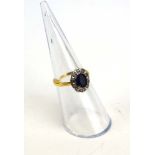An 18ct yellow gold cluster ring set oval sapphire within a border of ten small diamonds,