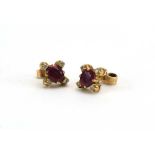 A pair of yellow metal ear studs, each set an oval ruby and four small diamonds, setting w. 9 mm, 1.