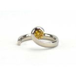 A modern platinum torque design ring set fancy yellow diamond in a tension setting,