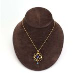 An Edwardian 9ct yellow gold fine chainlink necklace suspending an openwork pendant set blue glass,