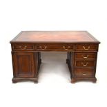 A late 19th/early 20th century mahogany and tooled leather partner's desk on plinth bases,