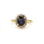 A yellow metal cluster ring set oval sapphire in a border of twelve small diamonds, ring size P, 4.