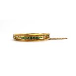 An early 20th century 9ct yellow gold hinged bracelet set eleven graduated emeralds and diamond