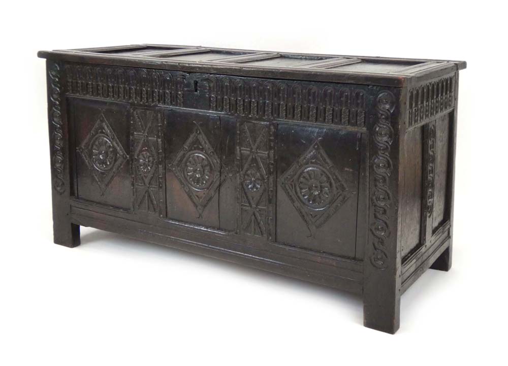 A 17th century and later oak panelled coffer with a carved frieze and stiles, c. 1620, l.