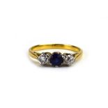 A yellow metal three stone ring set vibrant blue sapphire and two diamonds, stones approximately 0.