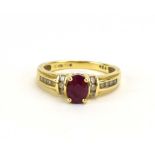 A modern 18ct yellow gold ring set oval ruby in a four claw setting with diamond set shoulders,