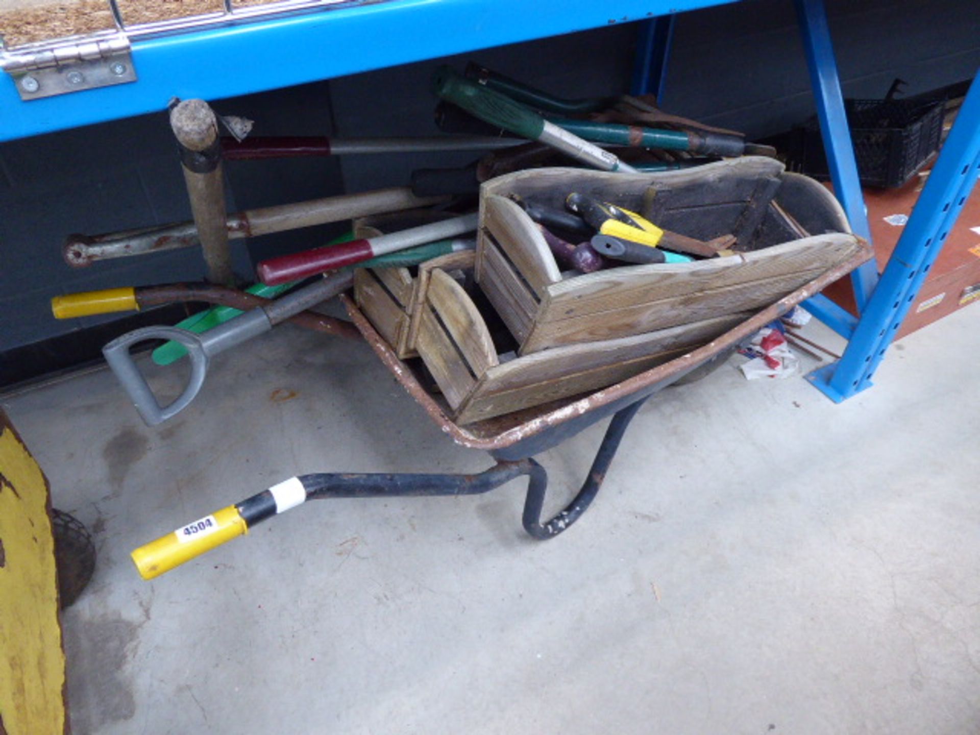 Wheelbarrow containing wooden planters, garden tools to include spades, forks, edging shears, saws