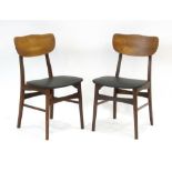 A pair of 1960's Danish dining chairs with shaped teak backs and black seats
