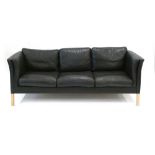 A 1970's black three seater sofa on beech square legs, l.